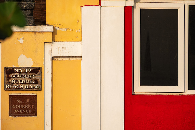 Red, yellow, black, and white geometric sections on a building facade in Puducherry.